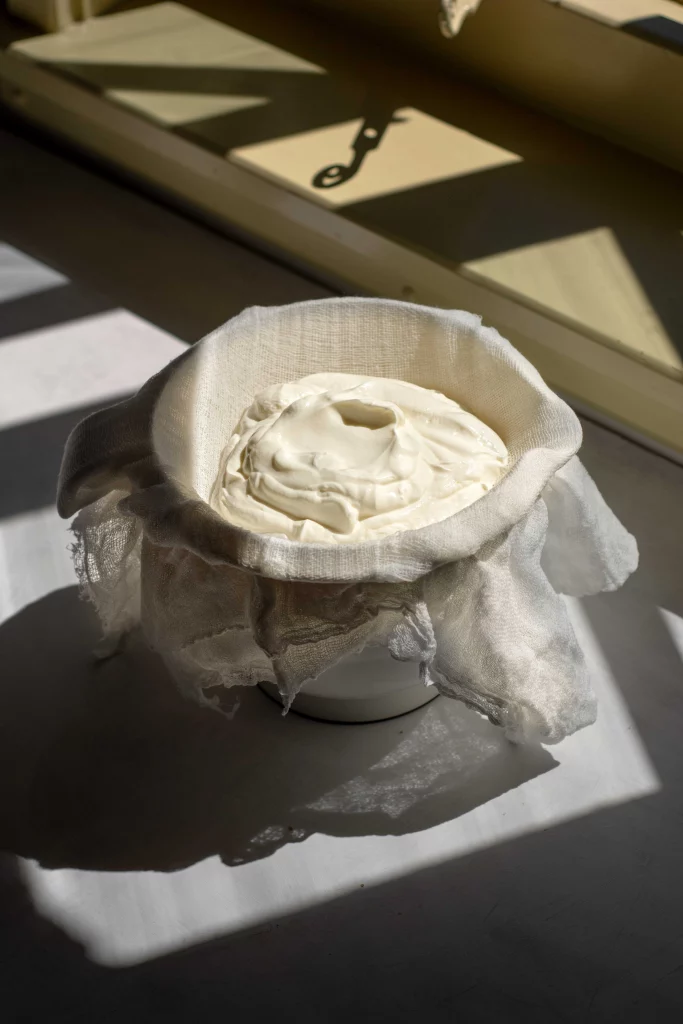 Greek yogurt strained through a muslin cloth and into a bowl
